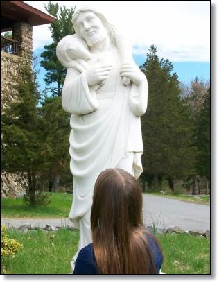 Young girl looking at Good Shepherd statue