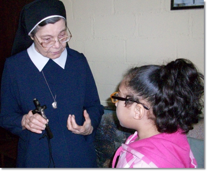 A Sister teaching a girl with the use of a crucifix